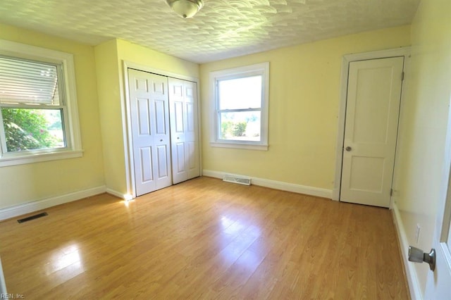 unfurnished bedroom with a textured ceiling, a closet, and light wood-type flooring