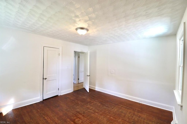 unfurnished room with dark wood-type flooring