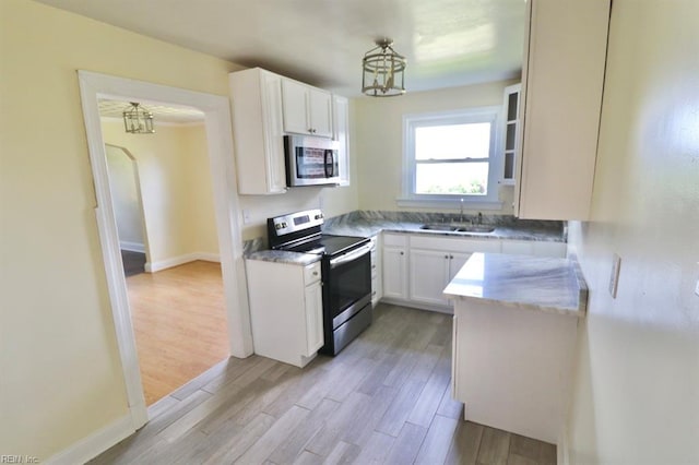 kitchen featuring stainless steel appliances, sink, white cabinetry, and light hardwood / wood-style flooring