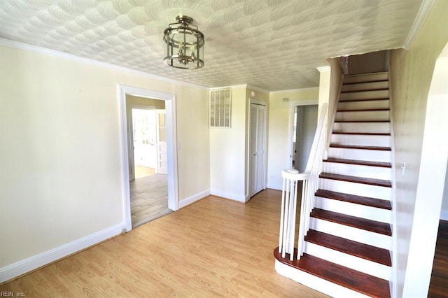 stairway featuring crown molding, hardwood / wood-style floors, and a chandelier