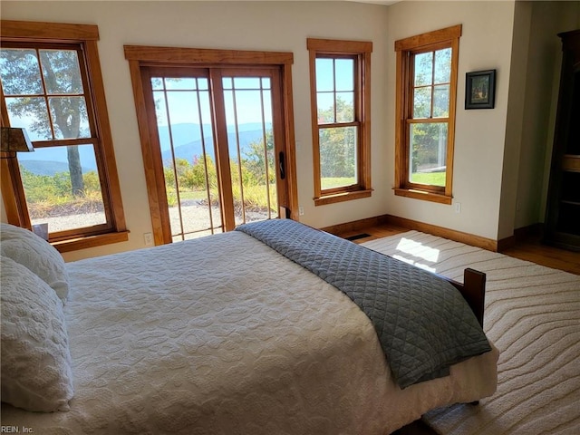 bedroom with multiple windows and hardwood / wood-style flooring