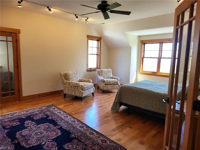 bedroom with ceiling fan, hardwood / wood-style flooring, lofted ceiling, and multiple windows