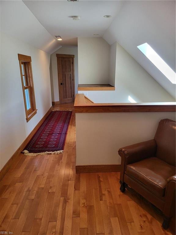 interior space featuring light hardwood / wood-style floors and lofted ceiling with skylight