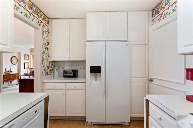 kitchen featuring light wood-type flooring, tasteful backsplash, white appliances, and white cabinetry