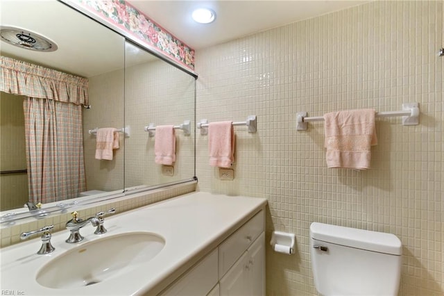 bathroom featuring tile walls, vanity, and toilet