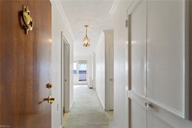 hall with ornamental molding and an inviting chandelier