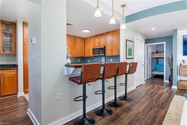 kitchen with a breakfast bar, pendant lighting, and dark hardwood / wood-style floors