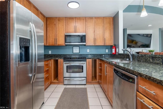 kitchen featuring sink, light tile patterned floors, stainless steel appliances, and decorative light fixtures