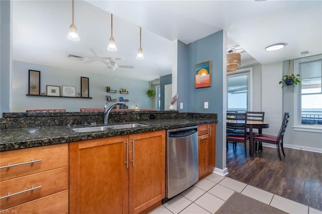 kitchen featuring ceiling fan, sink, stainless steel dishwasher, dark stone countertops, and light wood-type flooring