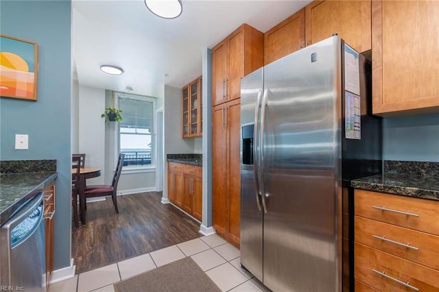 kitchen featuring stainless steel appliances, light hardwood / wood-style floors, and dark stone counters