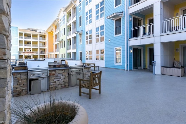 view of patio featuring a balcony, an outdoor kitchen, and a grill