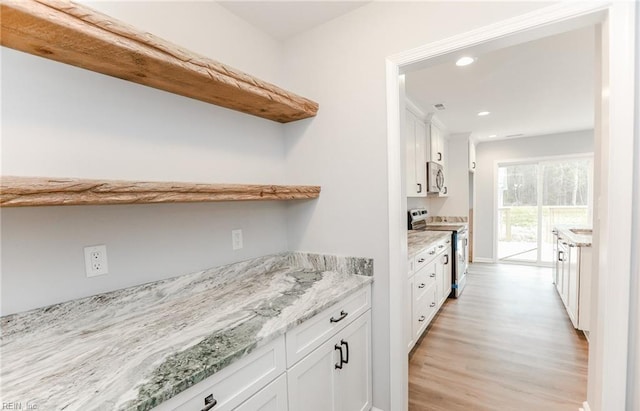 kitchen featuring white cabinetry, light hardwood / wood-style floors, light stone counters, and appliances with stainless steel finishes