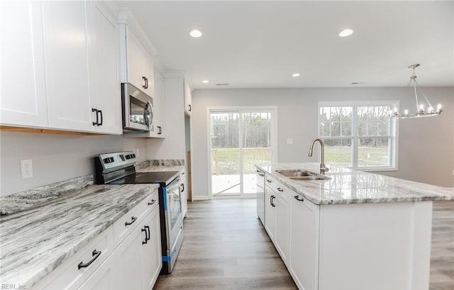 kitchen with appliances with stainless steel finishes, white cabinetry, a kitchen island with sink, and sink