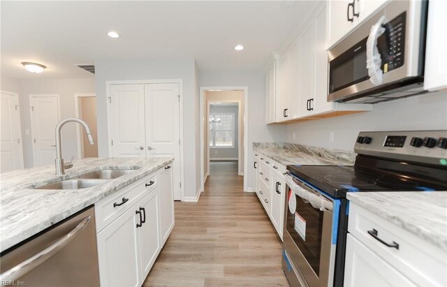 kitchen featuring light stone counters, sink, white cabinets, and appliances with stainless steel finishes