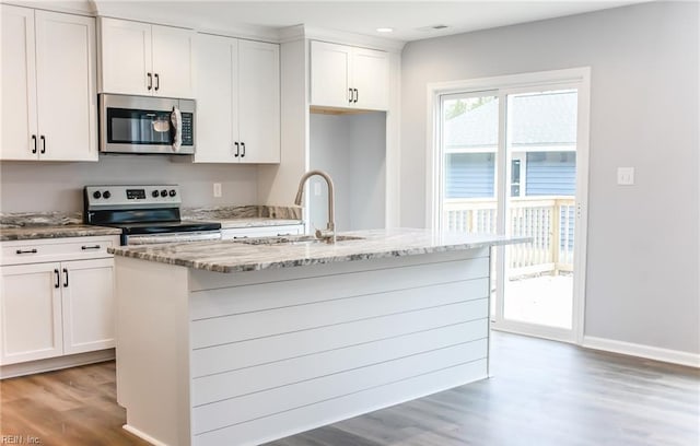 kitchen featuring stainless steel appliances, a kitchen island with sink, sink, hardwood / wood-style flooring, and white cabinetry