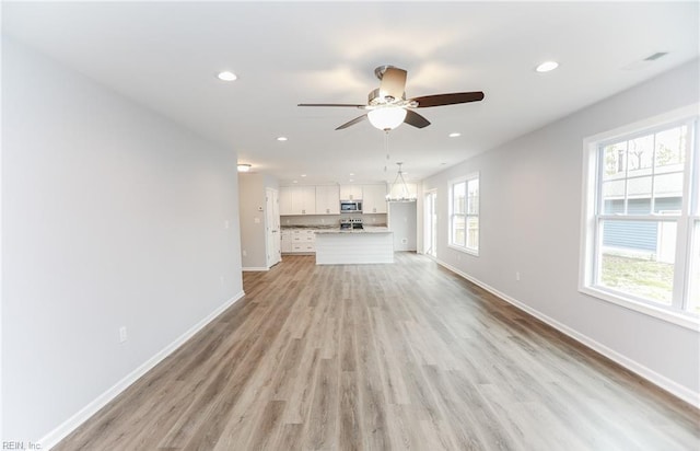 unfurnished living room featuring light hardwood / wood-style flooring, ceiling fan, and a healthy amount of sunlight