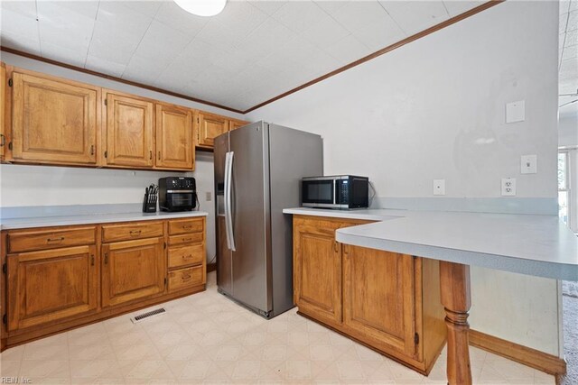 kitchen with appliances with stainless steel finishes, kitchen peninsula, and ornamental molding