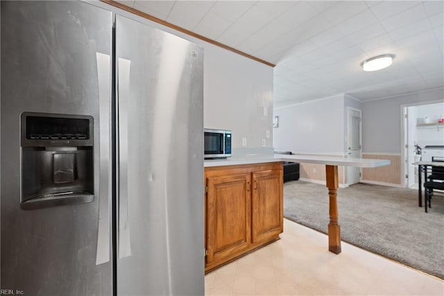 kitchen with light carpet, appliances with stainless steel finishes, and crown molding