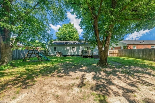 rear view of house with a playground, a yard, and a wooden deck