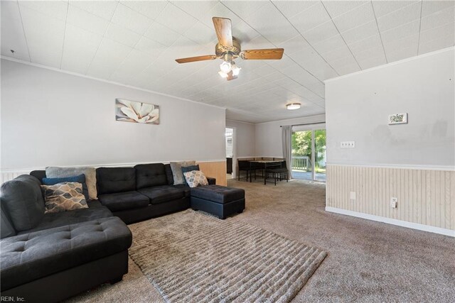 carpeted living room featuring ornamental molding and ceiling fan