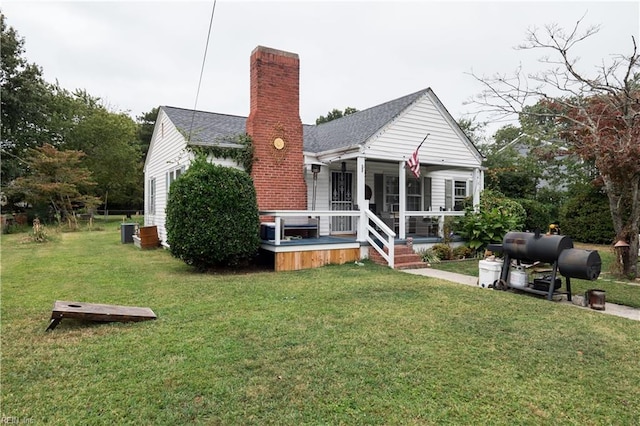 back of property with a sunroom, a lawn, and central AC