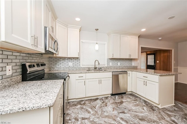 kitchen featuring kitchen peninsula, light stone countertops, stainless steel appliances, decorative light fixtures, and sink