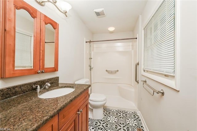 bathroom featuring vanity, a shower, tile patterned flooring, and toilet