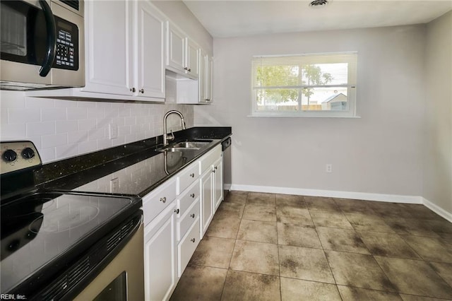 kitchen with dark stone countertops, white cabinetry, backsplash, stainless steel appliances, and sink