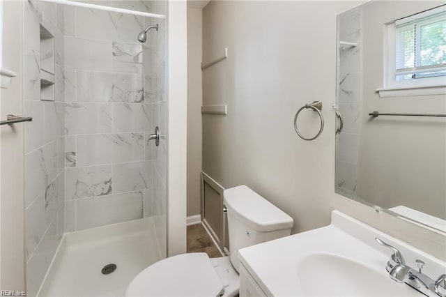 bathroom featuring vanity, toilet, and tiled shower