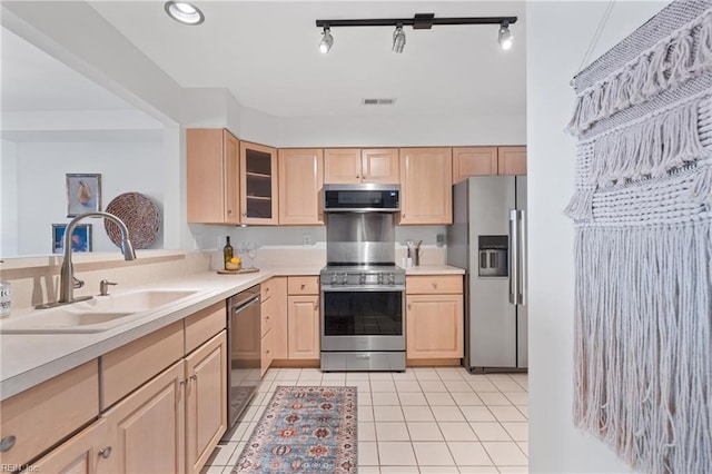 kitchen featuring stainless steel appliances, light brown cabinetry, light tile patterned floors, and sink