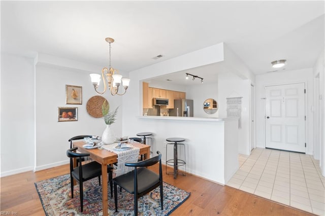 dining room with a notable chandelier, light hardwood / wood-style floors, and rail lighting