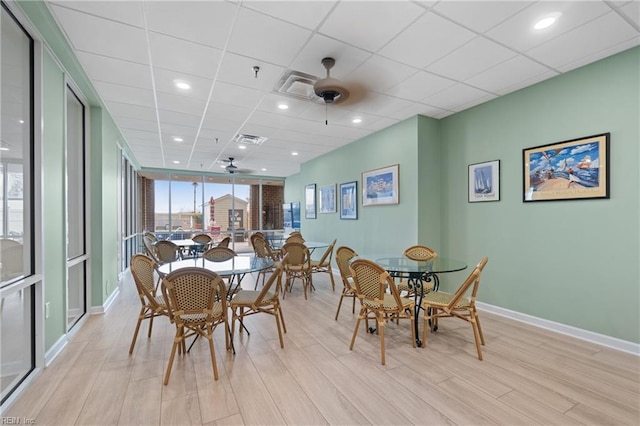 dining space featuring a drop ceiling, light hardwood / wood-style floors, and ceiling fan