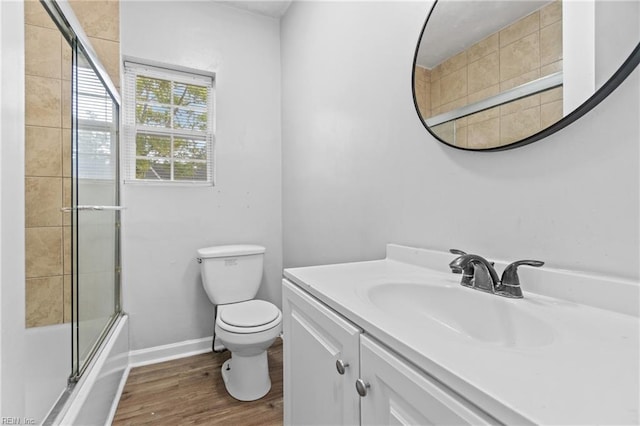 full bathroom featuring wood-type flooring, combined bath / shower with glass door, vanity, and toilet