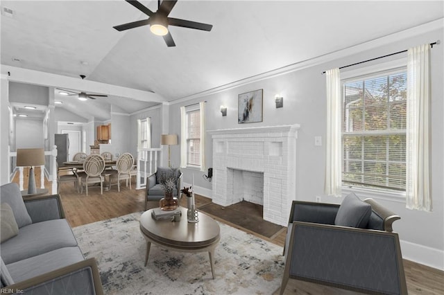 living room featuring lofted ceiling, a fireplace, dark hardwood / wood-style floors, and ceiling fan