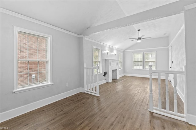 unfurnished living room with a brick fireplace, crown molding, ceiling fan, hardwood / wood-style flooring, and vaulted ceiling with beams