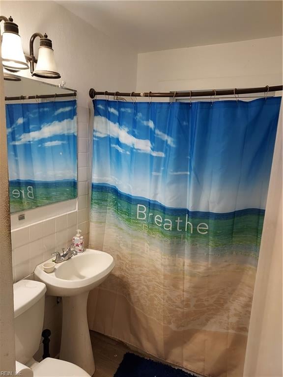 bathroom featuring tile walls, curtained shower, toilet, and backsplash