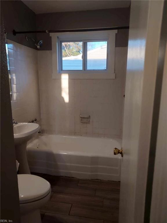 bathroom featuring wood-type flooring, tiled shower / bath combo, and toilet