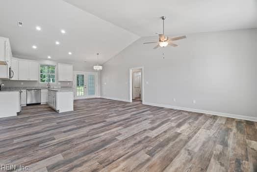 kitchen with lofted ceiling, white cabinetry, wood-type flooring, and stainless steel dishwasher