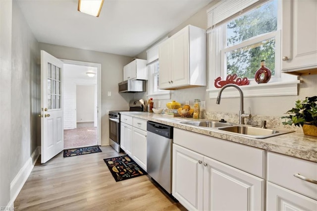 kitchen featuring stainless steel appliances, white cabinetry, light hardwood / wood-style floors, and sink