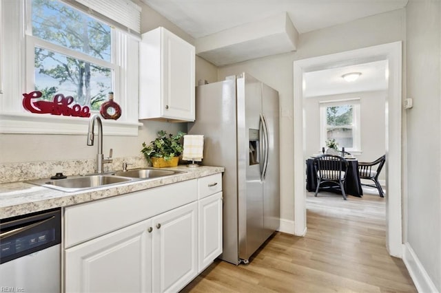 kitchen featuring appliances with stainless steel finishes, light wood-type flooring, white cabinetry, and sink