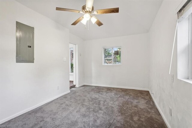 spare room with dark carpet, ceiling fan, and electric panel