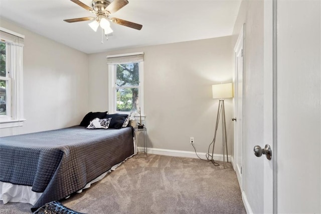 bedroom featuring ceiling fan, light colored carpet, and multiple windows