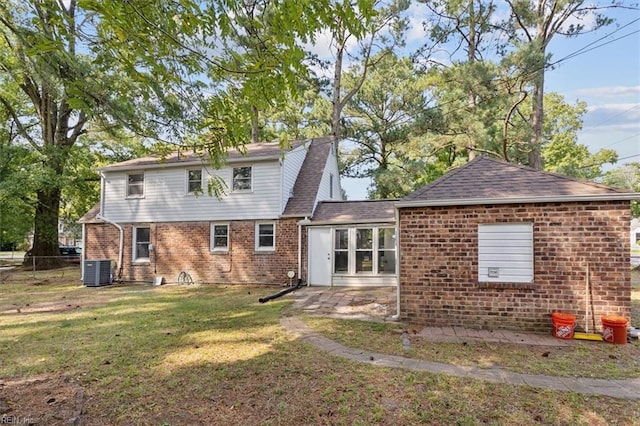 back of property featuring a lawn and central air condition unit