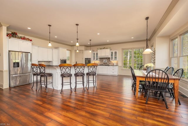 kitchen with white cabinetry, appliances with stainless steel finishes, decorative light fixtures, and dark hardwood / wood-style flooring