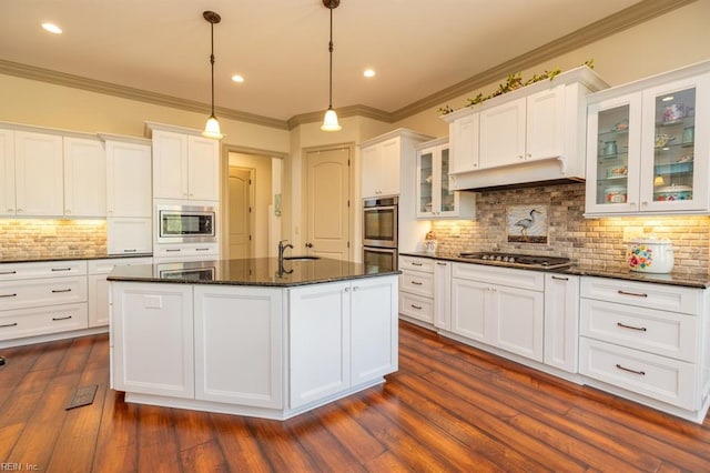 kitchen featuring dark hardwood / wood-style flooring, pendant lighting, an island with sink, and white cabinets