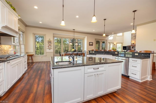 kitchen with appliances with stainless steel finishes, a kitchen island with sink, dark hardwood / wood-style floors, and pendant lighting