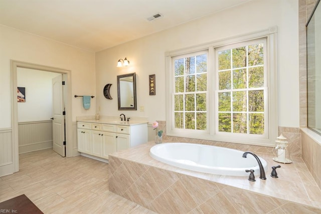 bathroom featuring tiled tub and vanity