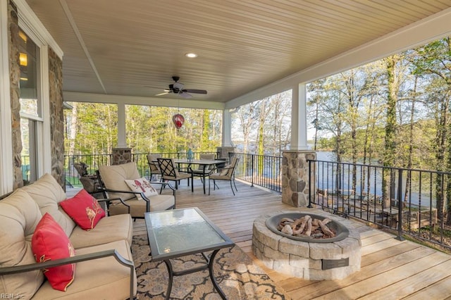 deck featuring ceiling fan and an outdoor living space with a fire pit