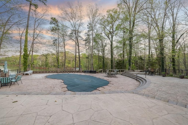 pool at dusk featuring a patio