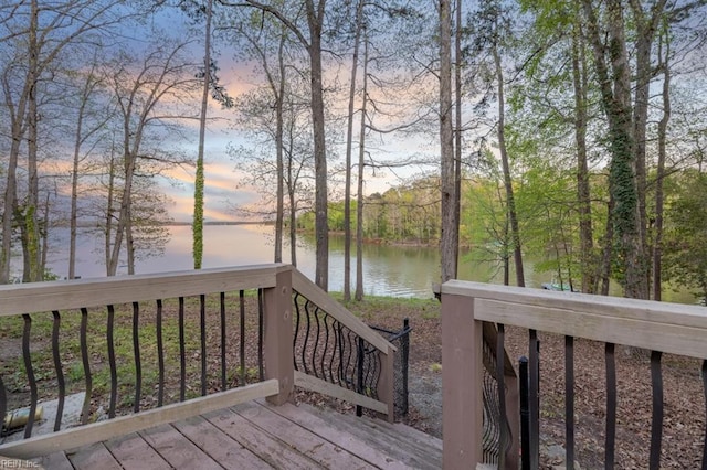 deck at dusk featuring a water view